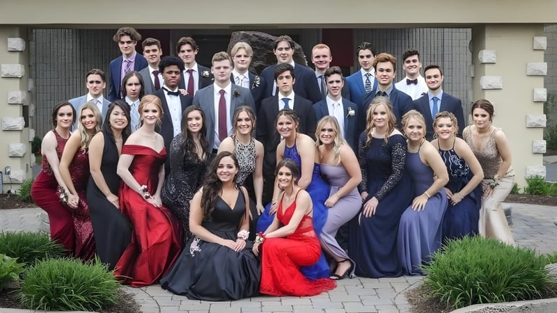 Eine Gruppe formal gekleideter Personen posiert im Außenbereich der Ontario Hockey Academy auf einem gepflasterten Weg mit Grünflächen im Hintergrund.