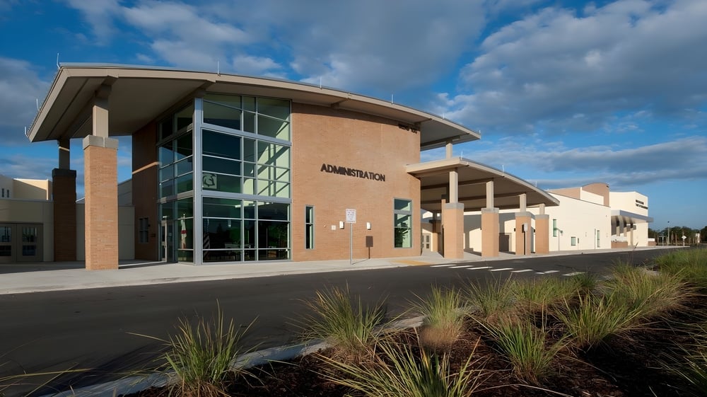 Ein modernes Gebäude mit Glasfront und geschwungenem Dach auf dem Gelände der Orange County Public Schools.