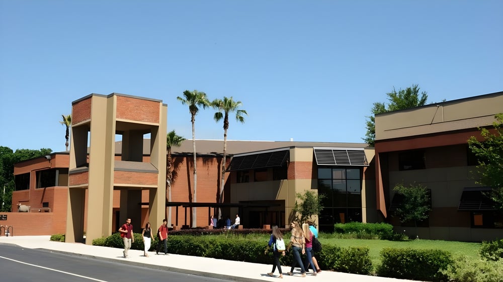 Das moderne Backsteingebäude der Orangewood Christian School mit Palmen und Menschen im Vordergrund.