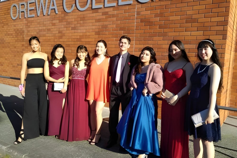 Eine Gruppe von Schülern steht vor dem Backsteingebäude des Orewa College.