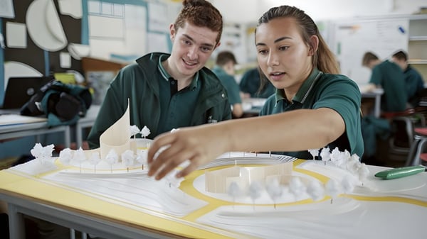 Zwei Schülerinnen und Schüler arbeiten gemeinsam an einem Projekt an einem Tisch im Klassenraum des Orewa College.