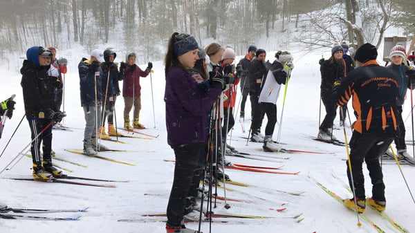 Eine Gruppe von Schülerinnen und Schülern der Orillia Secondary School steht auf Skiern in einem verschneiten Wald.