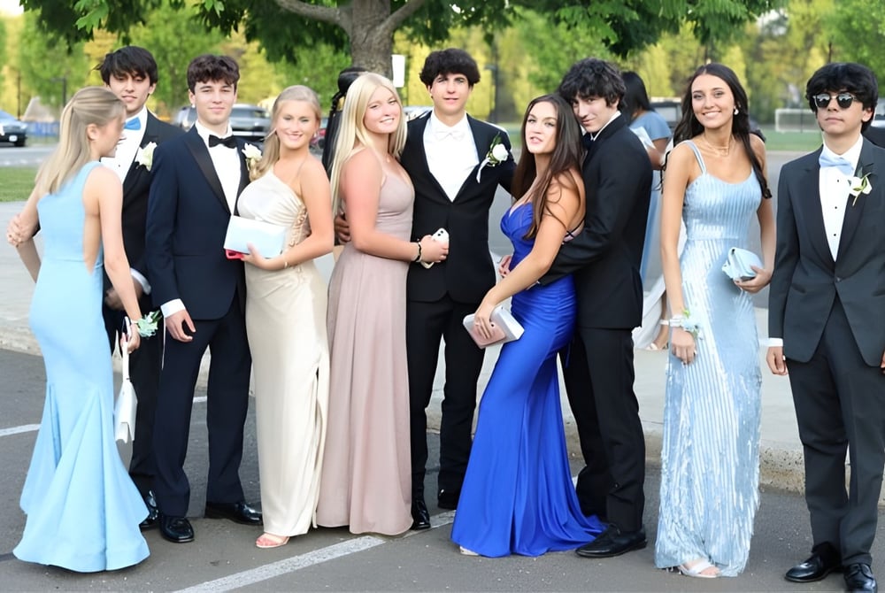 Eine Gruppe von Personen posiert im Park auf dem Campus der Oromocto High School vor üppigem Grün.