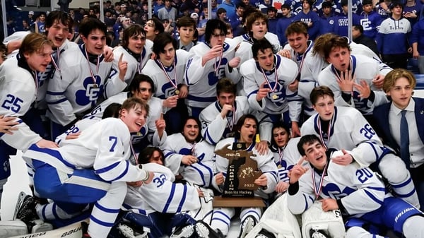 Schüler der Oromocto High School feiern mit einer Trophäe nach einem Hockeyspiel vor Zuschauern.