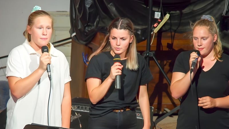 Drei Schülerinnen der Orroroo Area School singen gemeinsam in Mikrofone auf der Bühne.