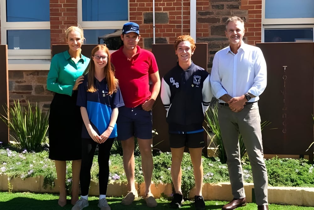 Eine Gruppe von fünf Personen steht vor dem Backsteingebäude mit blauen Fenstern auf dem Campus der Orroroo Area School.