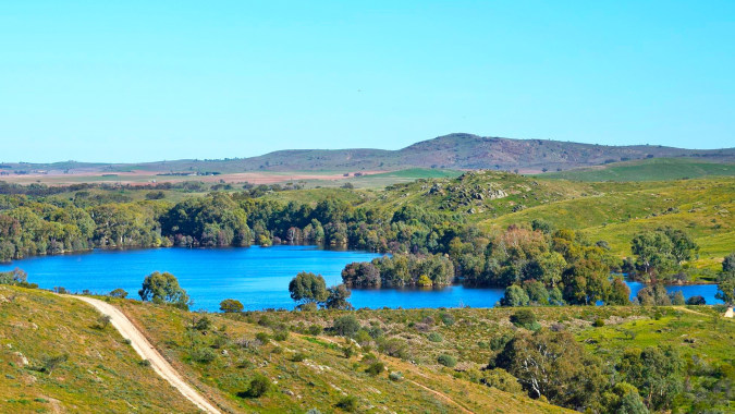 Landschaft mit blauem See und grünen Hügeln vor Bergen, nahe der Orroroo Area School.