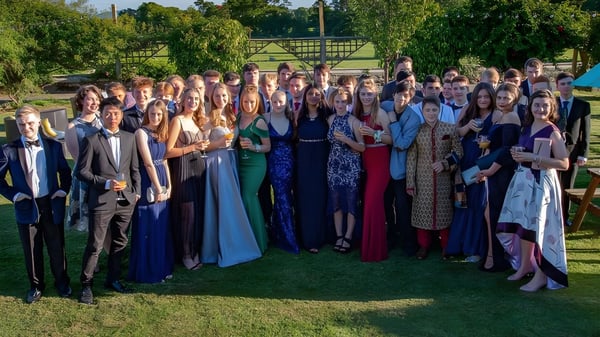 Eine große Gruppe von formal gekleideten Schülerinnen und Schülern steht auf einer Wiese auf dem Campus der Oswestry School.