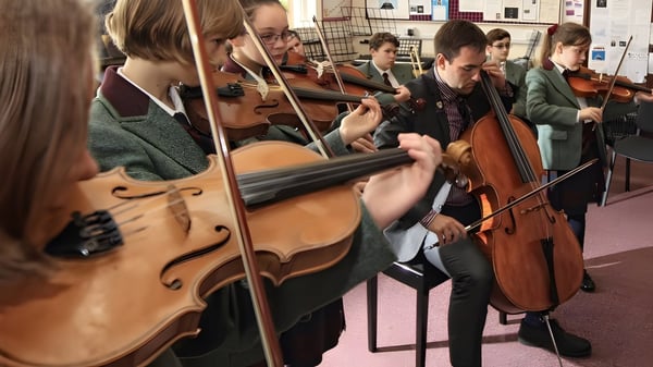 Eine Gruppe von Musikerinnen und Musikern der Oswestry School probt gemeinsam in einem Raum mit Musikinstrumenten.