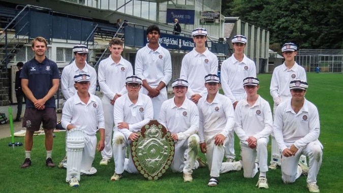 Eine Gruppe von Cricket-Spielern der Otago Boys' High School steht auf einem Feld und hält gemeinsam einen Pokal.