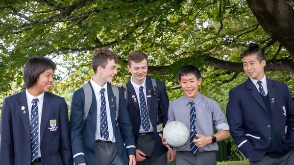 Eine Gruppe Schüler der Otago Boys' High School steht gemeinsam in einer grünen Außenanlage.