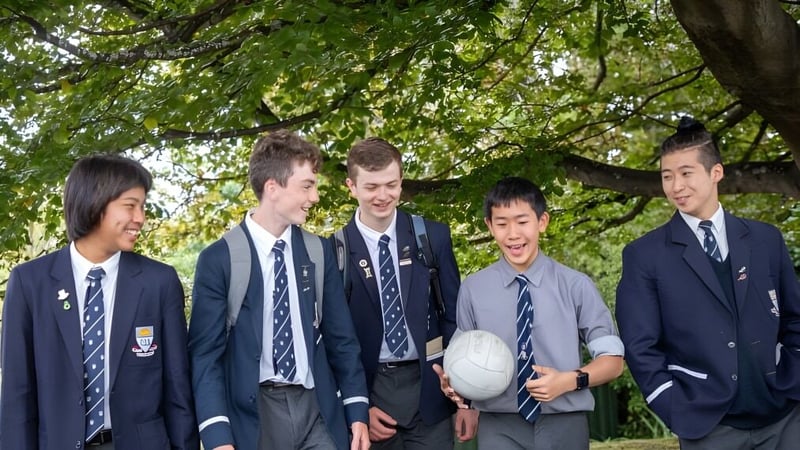 Eine Gruppe Schüler der Otago Boys' High School steht gemeinsam in einer grünen Außenanlage.