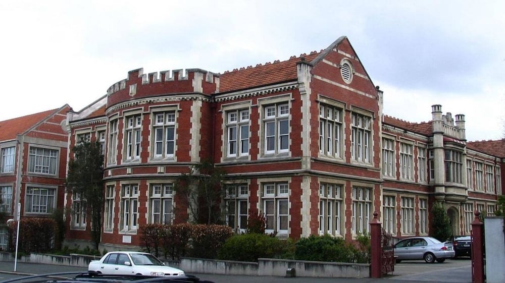Das große, verzierte Backsteingebäude der Otago Girls High School ist von Bäumen umgeben.
