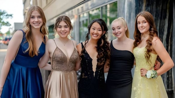 Fünf Schülerinnen der Otago Girls High School posieren lächelnd vor einem Gebäude mit Glasfenstern.
