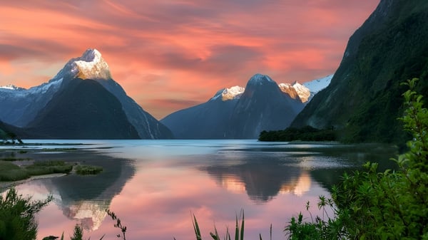 Majestätische schneebedeckte Berge spiegeln sich bei Sonnenuntergang in den ruhigen Gewässern eines Fjords nahe der Otago Girls High School.