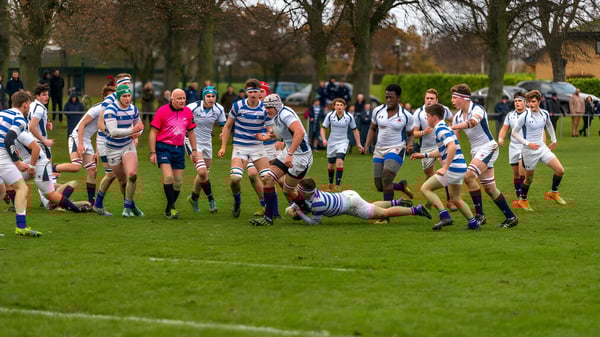 Ein Rugby-Spiel mit Spielern im gestreiften Trikot findet auf dem Rasen der Oundle School statt.