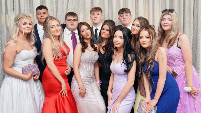 Eine Gruppe Schülerinnen und Schüler des Our Lady Catholic College posiert in formeller Kleidung vor einem Vorhang.