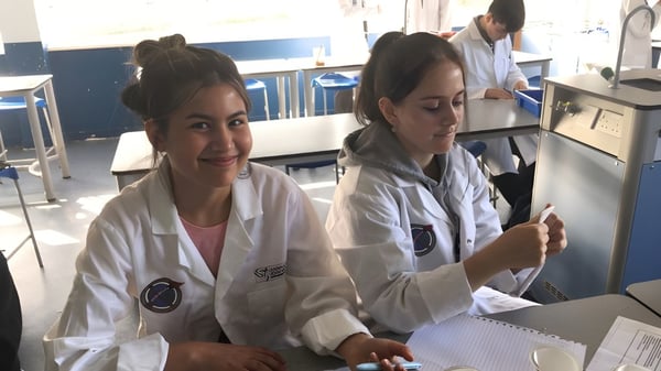 Zwei Schülerinnen im Labor des Our Lady Catholic College tragen weiße Laborkittel und arbeiten mit medizinischem Gerät.