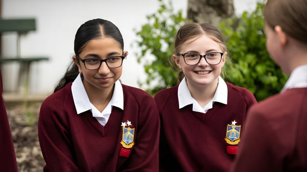 Zwei Schülerinnen in Schuluniform stehen auf einer Wiese auf dem Campus des Our Lady Catholic College.
