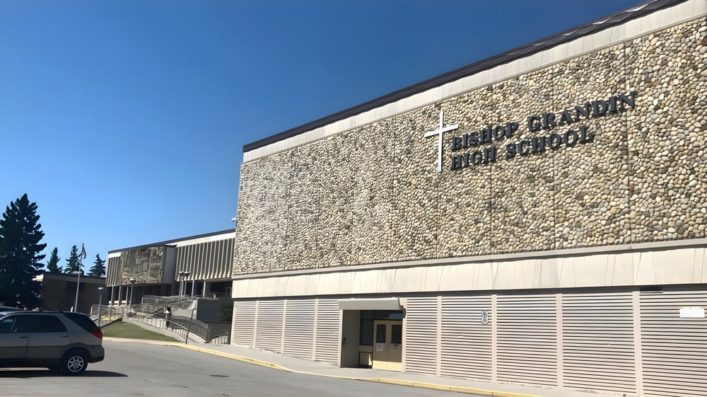 Das Hauptgebäude der Our Lady of the Rockies High School mit Steinfassade und klar blauem Himmel im Hintergrund.