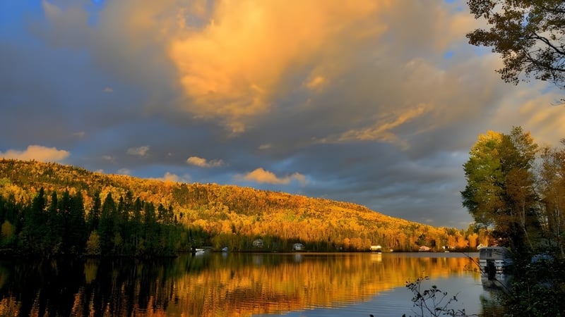 Ein ruhiger See mit herbstlicher Laubfärbung unter bewölktem Himmel in der Nähe der Our Lady of the Rockies High School.