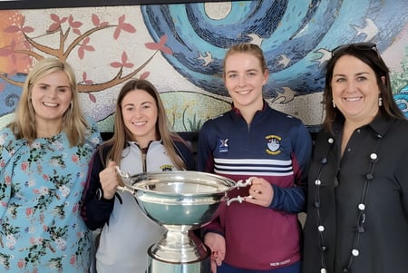 Vier Schülerinnen der Our Lady´s Bower Secondary School halten gemeinsam einen Pokal vor einer farbenfrohen Wandmalerei.