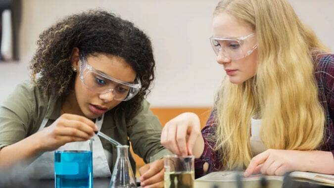 Zwei Schülerinnen des Our Lady's College konzentrieren sich auf ein wissenschaftliches Experiment im Klassenraum.