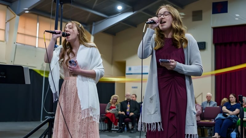 Zwei Schülerinnen der Overland Christian Schools singen auf der Bühne während einer Aufführung.