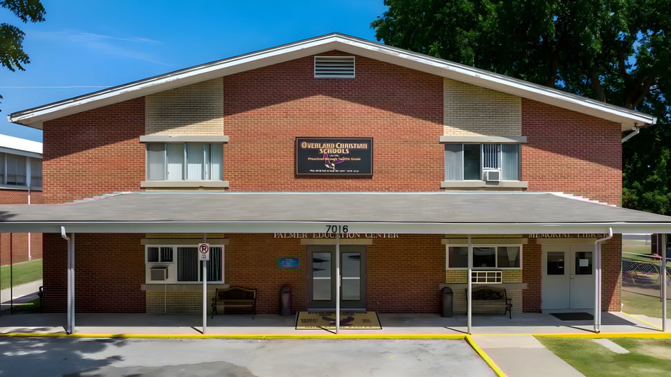 Das Coon Creek Community Center auf dem Gelände der Overland Christian Schools steht in einem grasbewachsenen Bereich mit Bäumen im Hintergrund.