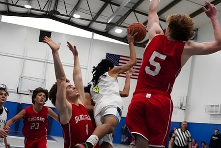 Schüler der Oxford Academy spielen ein Basketballspiel in der Sporthalle mit Zuschauern im Hintergrund.