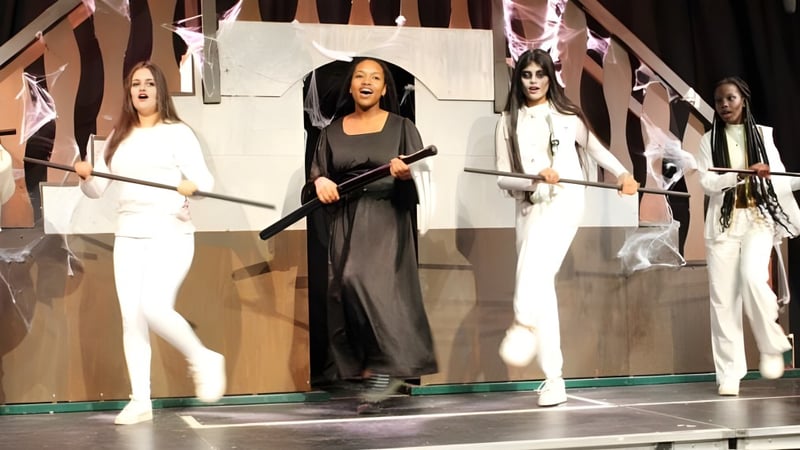 Eine Gruppe von Frauen steht auf der Bühne der Oxford Academy vor einem geometrischen Hintergrund.