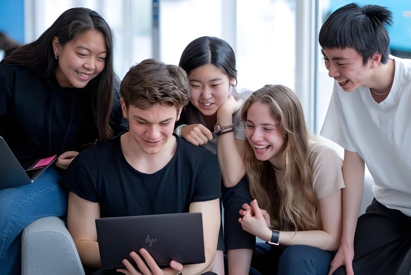 Schüler des Oxford International College Brighton arbeiten gemeinsam an einem Laptop.