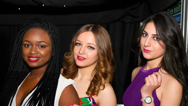 Drei Schülerinnen mit unterschiedlichen Hintergründen posieren gemeinsam vor einem dunklen Hintergrund am Oxford International College.