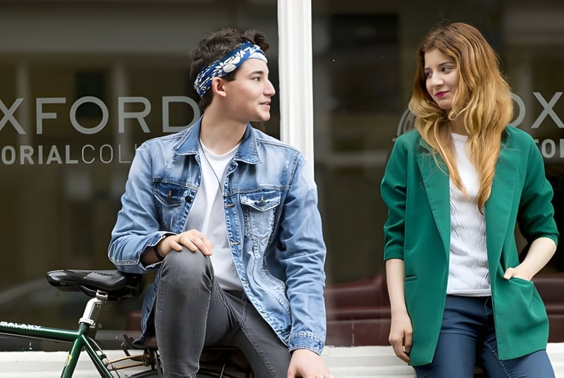 Zwei Schülerinnen und Schüler stehen vor dem Gebäude des Oxford Sixth Form College mit sichtbarem Schriftzug.