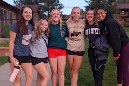 Eine Gruppe von Schülerinnen steht draußen auf einer Wiese mit Bäumen im Hintergrund auf dem Campus der Pacific Lutheran High School.