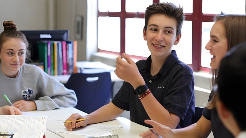 Drei Schülerinnen und Schüler der Pacifica Christian High School führen ein Gespräch in einem Klassenraum.