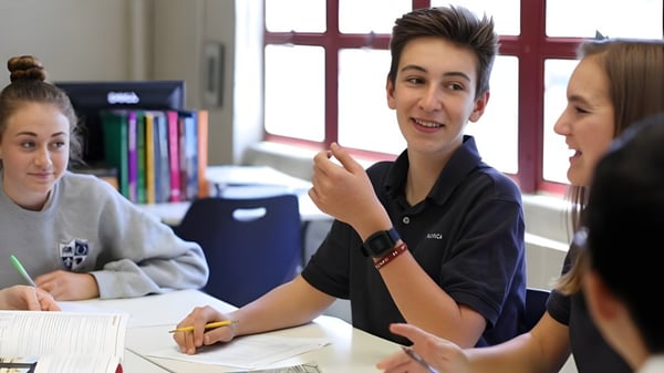 Drei Schülerinnen und Schüler der Pacifica Christian High School führen ein Gespräch in einem Klassenraum.