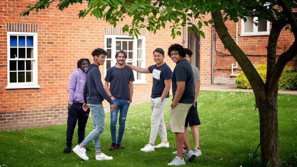 Eine Gruppe Schülerinnen und Schüler steht auf einer Wiese vor einem Backsteingebäude auf dem Campus des Padworth College.