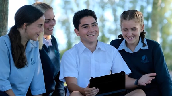 Eine Gruppe von Schülern steht zusammen und lächelt im Freien auf dem Gelände des Pakuranga College.