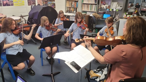 Schüler der Palm Beach Currumbin State High School spielen gemeinsam Musikinstrumente und lesen Noten in einem Klassenraum.