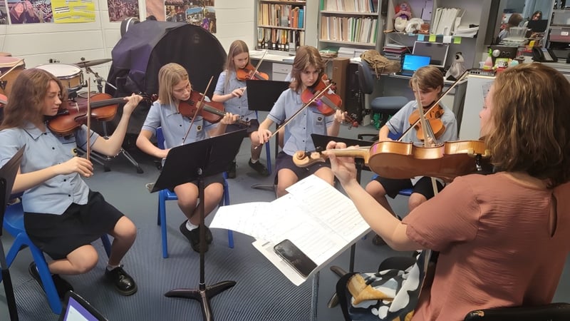 Schüler der Palm Beach Currumbin State High School spielen gemeinsam Musikinstrumente und lesen Noten in einem Klassenraum.