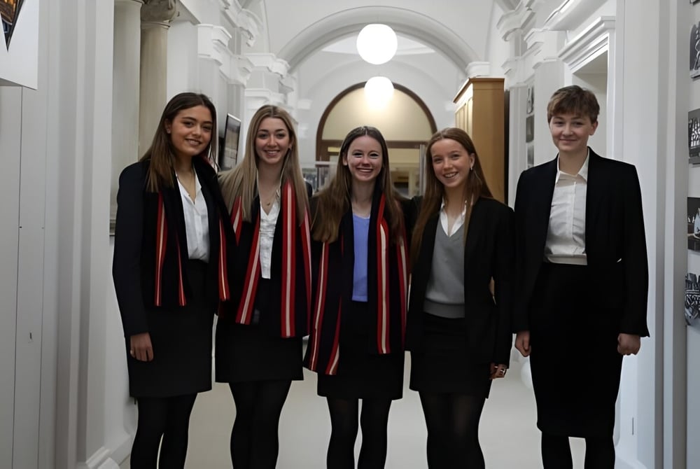 Fünf Jugendliche in formeller Kleidung stehen gemeinsam im Flur auf dem Campus des Pangbourne College.