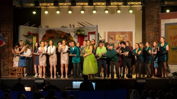 Eine Gruppe von Schülern der Panorama Ridge Secondary School steht in formeller Kleidung auf einer Bühne vor einer Backsteinwand.