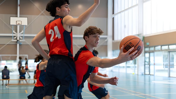 Zwei Basketballspieler kämpfen um den Ball auf dem Spielfeld des Papamoa College.