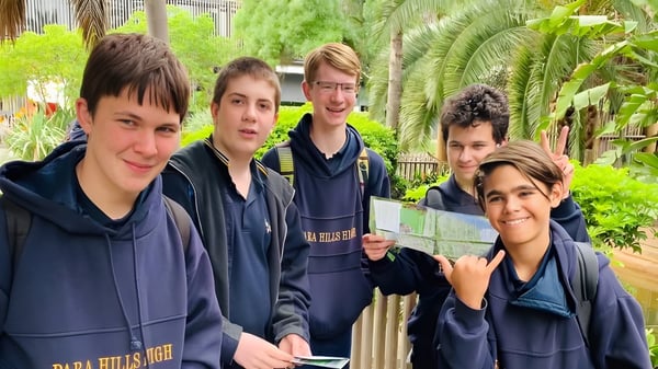 Eine Gruppe Schüler der Para Hills High School steht zusammen im tropisch gestalteten Schulhof.