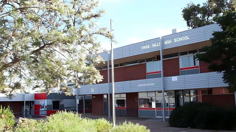 Das Gebäude der Para Hills High School steht umgeben von grünen Bäumen und Pflanzen.