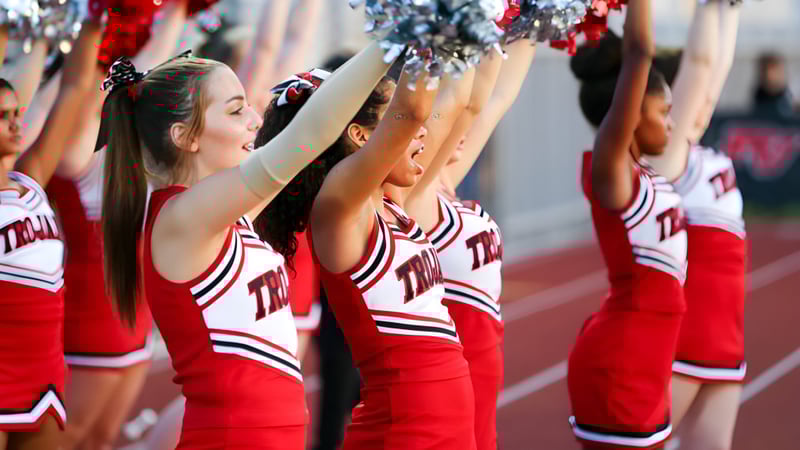 Eine Gruppe Cheerleader des Paradise Valley Unified School District führt eine Performance auf dem Sportfeld vor Zuschauern im Stadion durch.