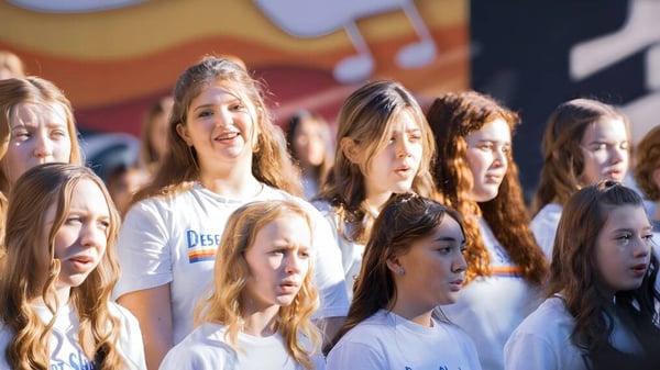 Eine Gruppe Schülerinnen des Paradise Valley Unified School District steht gemeinsam in einem Raum mit musikalischen Noten und Instrumenten im Hintergrund.