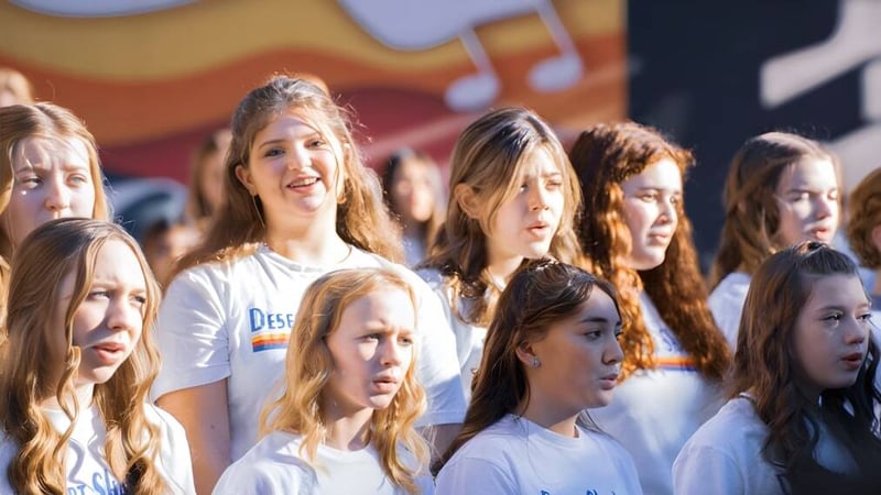 Eine Gruppe Schülerinnen des Paradise Valley Unified School District steht gemeinsam in einem Raum mit musikalischen Noten und Instrumenten im Hintergrund.