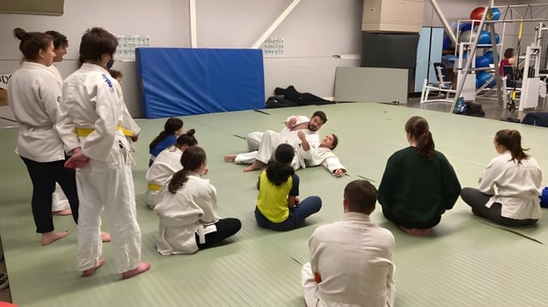 Eine Gruppe von Schülerinnen und Schülern der Parkland Secondary School übt gemeinsam Kampfsport auf einer Matte.